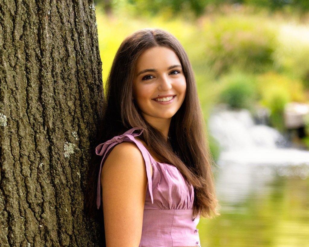 Smiling brunette woman standing against tree